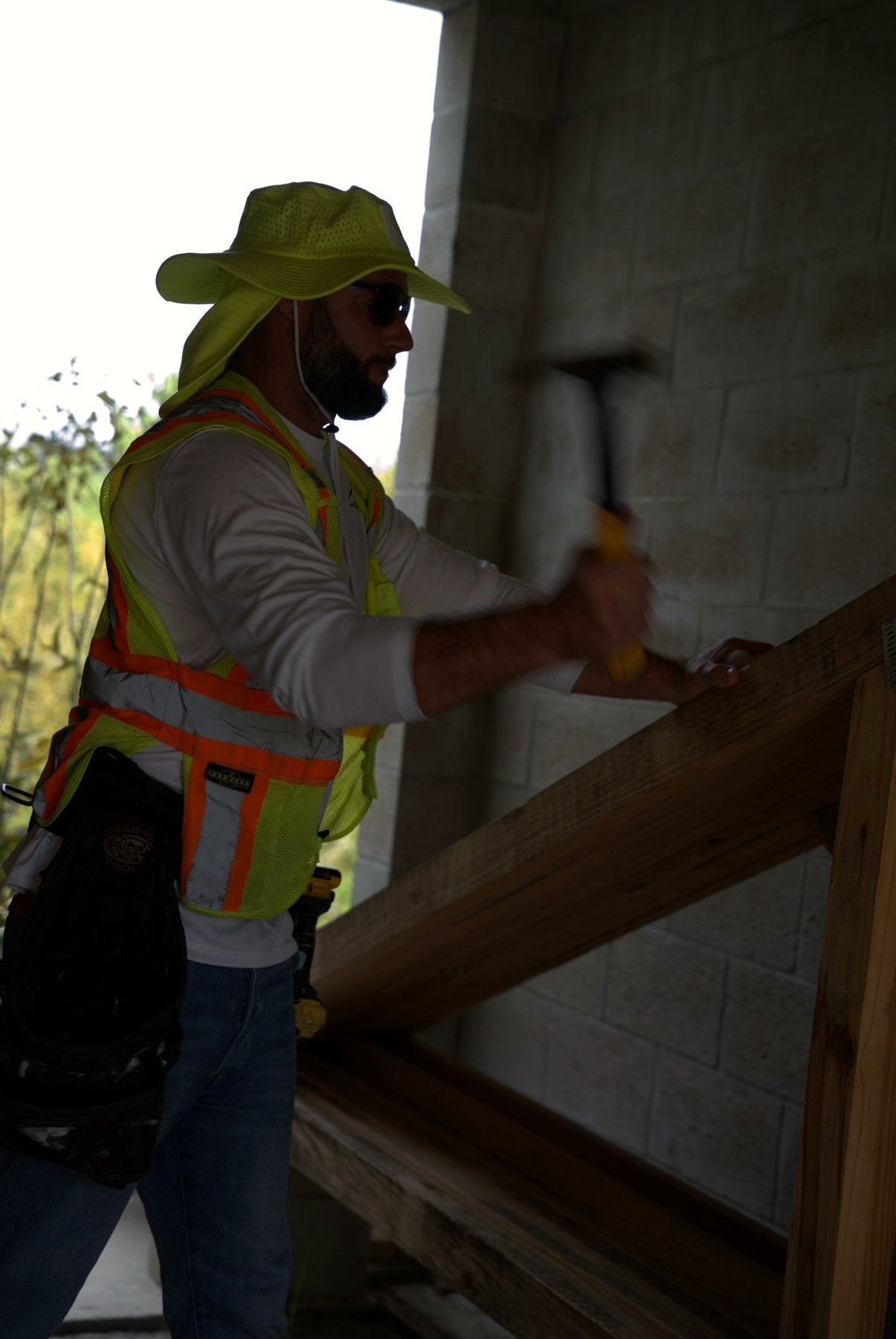 Crew member in a Safety Yellow Arctic Mullet hat on a job site