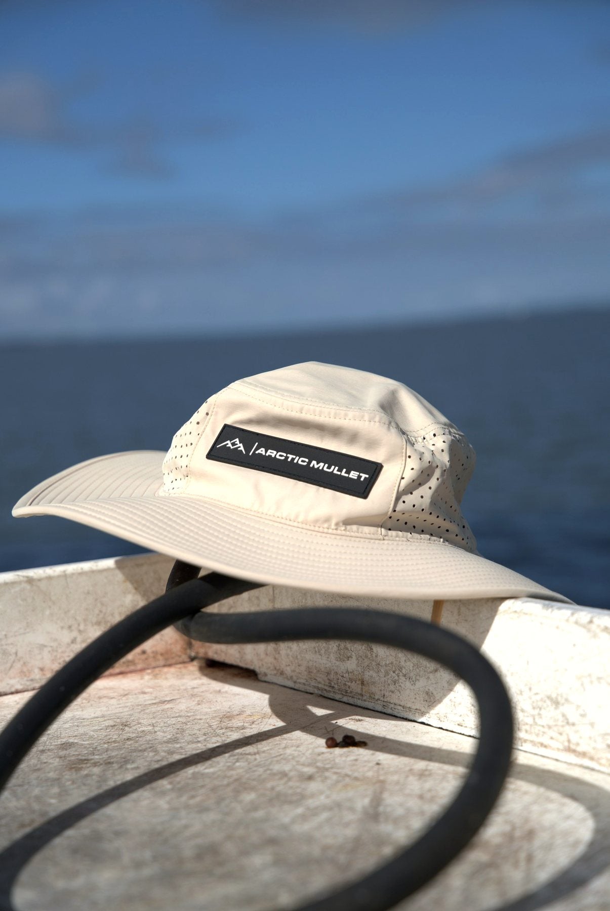 Khaki Arctic Mullet hat on a dock piling