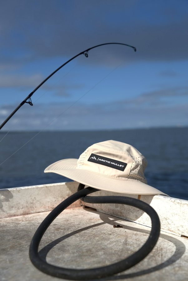 Hat on a boat rail beside a fishing rod