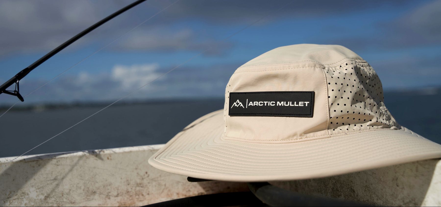 Khaki Arctic Mullet hat resting on a seawall