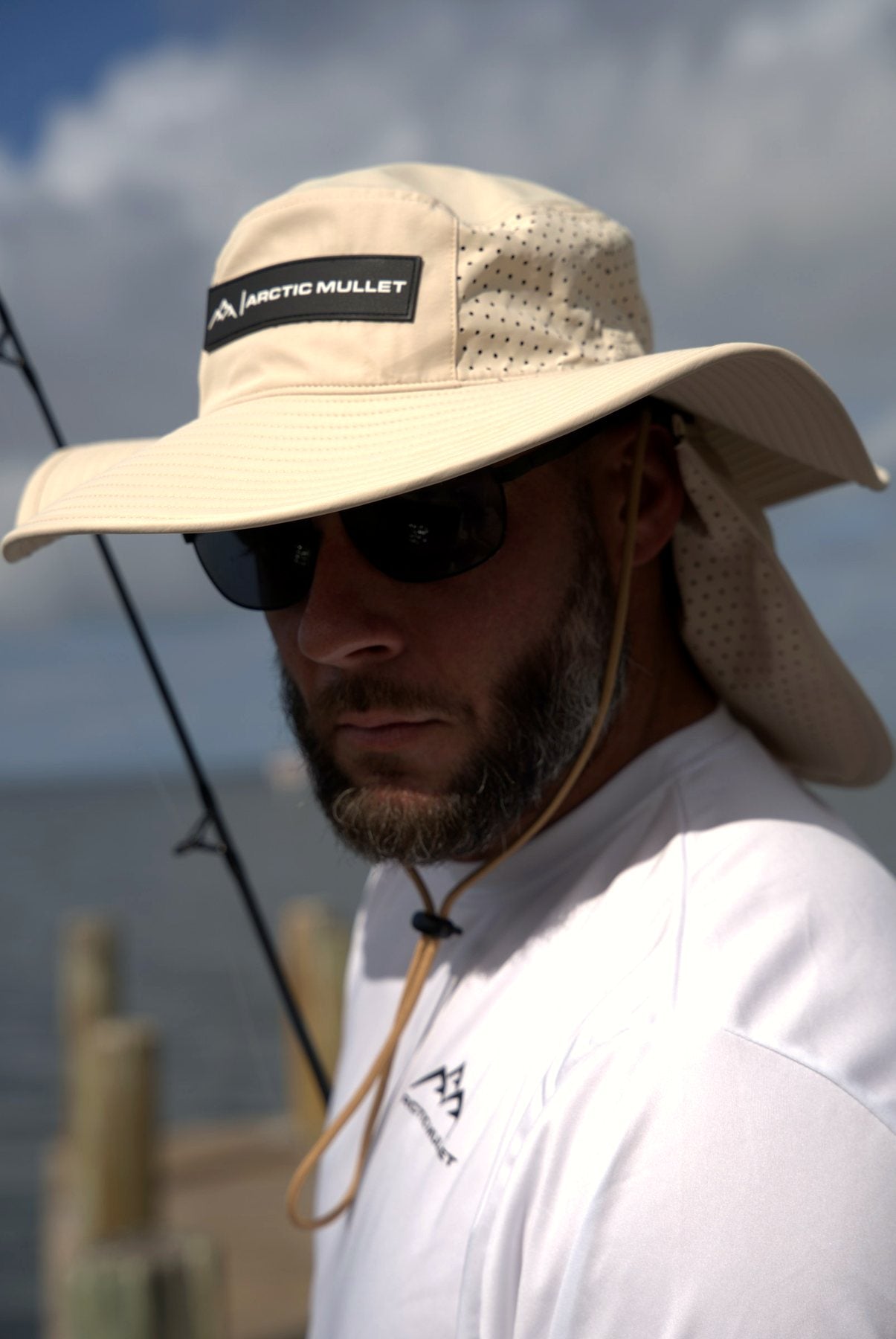 Man fishing from a Florida dock in the khaki Arctic Mullet cooling bucket hat