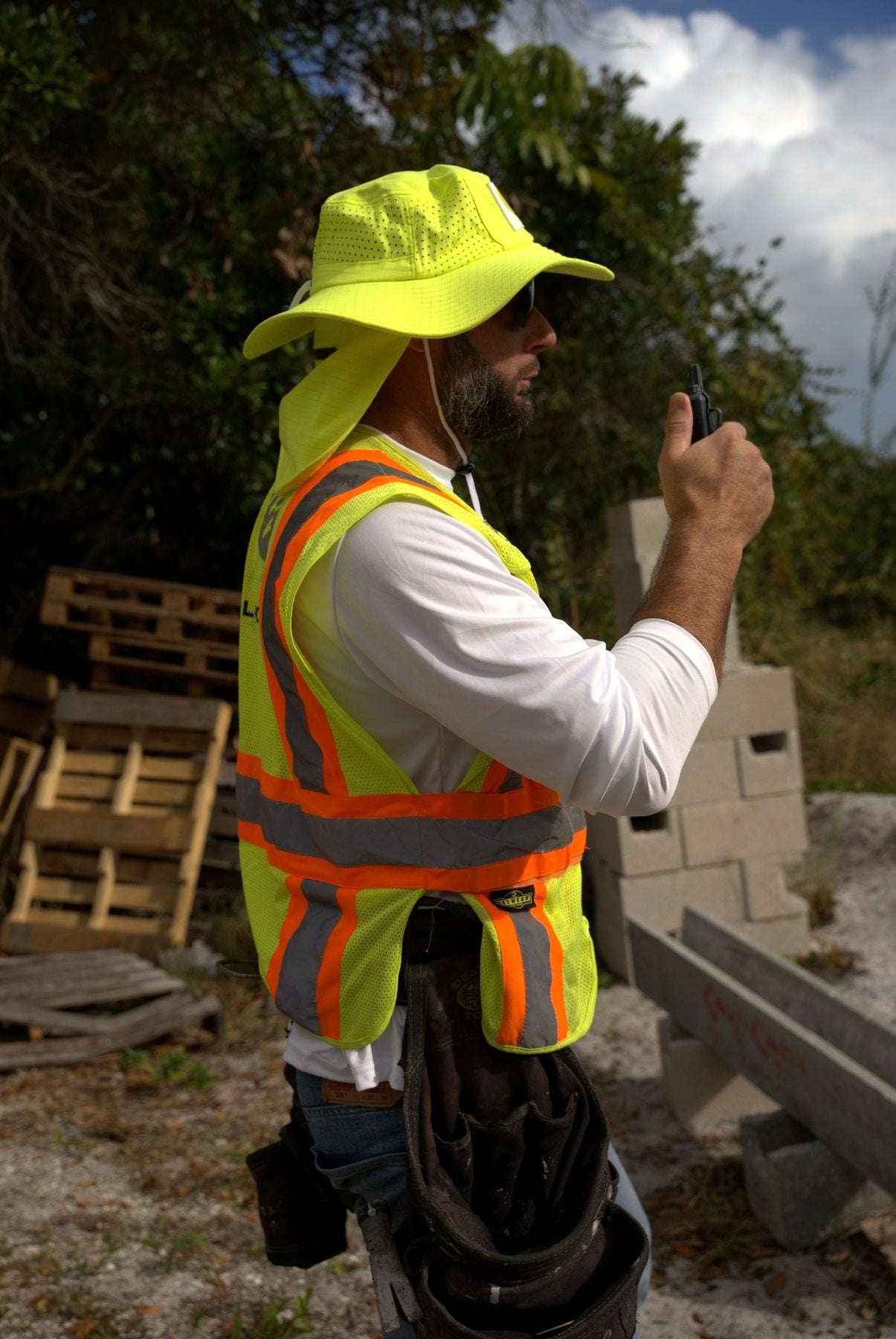 Worker in a Safety Yellow Arctic Mullet hat and hi-vis vest on a job site